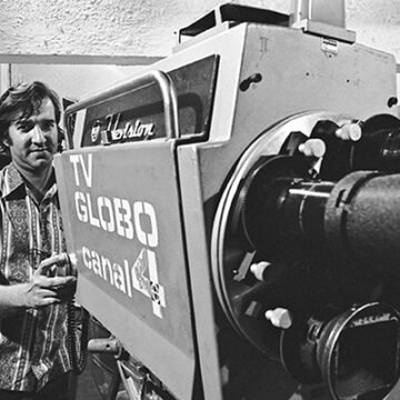 Atriz Maitê Proença, com outros artistas globais, relembrando os privilégios na TV Globo nos anos 70 e 80, em uma sala de reunião com diretores.
