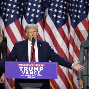 Imagem de Donald Trump discursando após as eleições de 2024, com um semblante de vitória e confiança em meio a uma multidão de apoiadores.