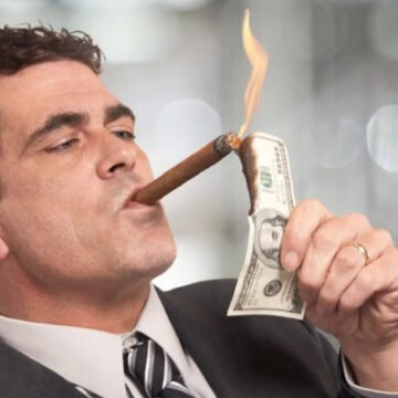 Uma pilha de cédulas de dinheiro ao lado de uma carteira aberta, representando escolhas financeiras conscientes.