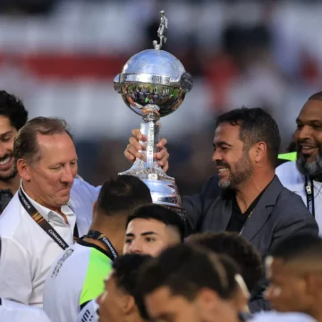 Torcedores do Botafogo celebrando a conquista da Libertadores 2024 com bandeiras e faixas no Monumental de Núñez.