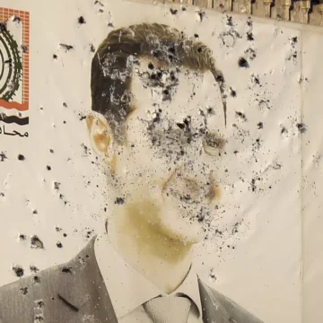 Civis celebrando a queda de Assad em Damasco com bandeiras e cartazes.