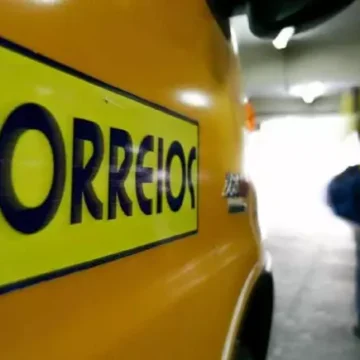 Uma mão segurando um celular com uma mensagem de texto suspeita dos Correios, com um fundo desfocado mostrando várias outras mensagens.