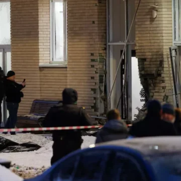 Foto da entrada destruída de um prédio residencial em Moscou, com paredes de tijolos escurecidas pela explosão, portas arrancadas e neve ao redor, simbolizando o ataque que matou o general russo Igor Kirillov.