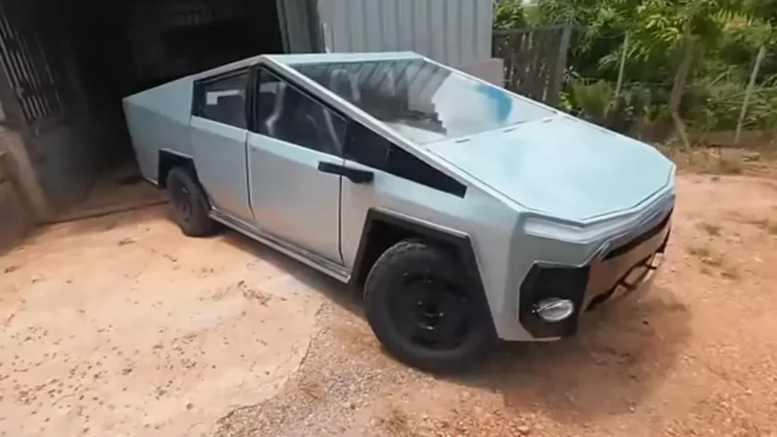 Lucas Carvalho posa ao lado de seu CyberFusca prateado, um carro com design futurista construído sobre um chassi de Fusca. O carro tem linhas retas e angulares, e uma caçamba na parte traseira.