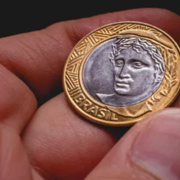 Cédulas de real espalhadas, com foco em notas de R$ 50, representando a desvalorização da moeda brasileira.