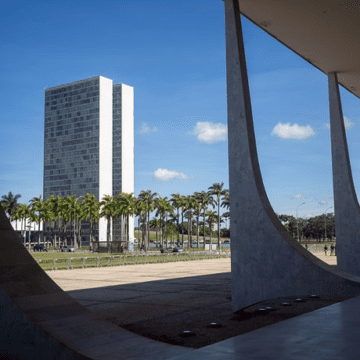 Uma imagem do Congresso Nacional em Brasília, com destaque para a arquitetura e a bandeira do Brasil ao fundo.
