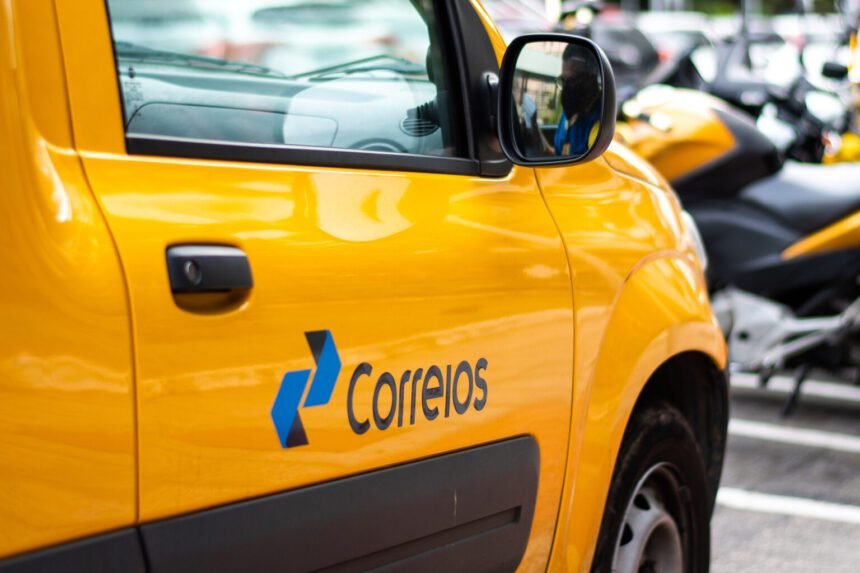 Fachada de uma agência dos Correios com placa visível, destacando o logotipo da estatal em amarelo e azul.