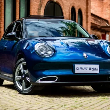 Um carro elétrico moderno na cor azul com detalhes em preto, estacionado ao ar livre, destacando o teto solar panorâmico e o design sofisticado
