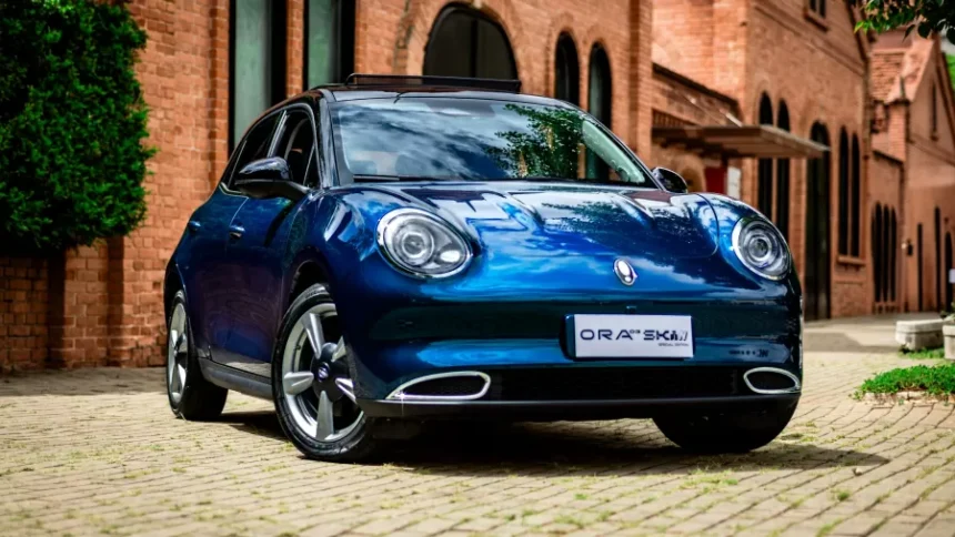 Um carro elétrico moderno na cor azul com detalhes em preto, estacionado ao ar livre, destacando o teto solar panorâmico e o design sofisticado