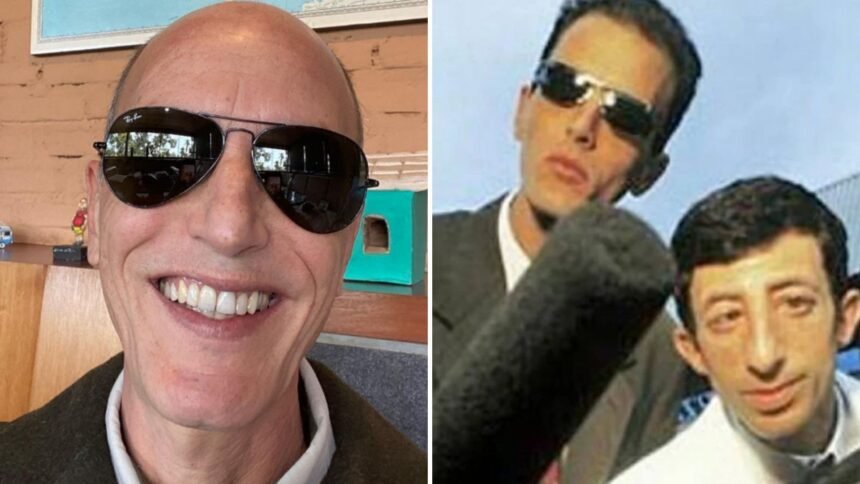 Rodolfo Carlos em sua casa, sorrindo, cercado por móveis clássicos que remetem a um ambiente confortável e simples.