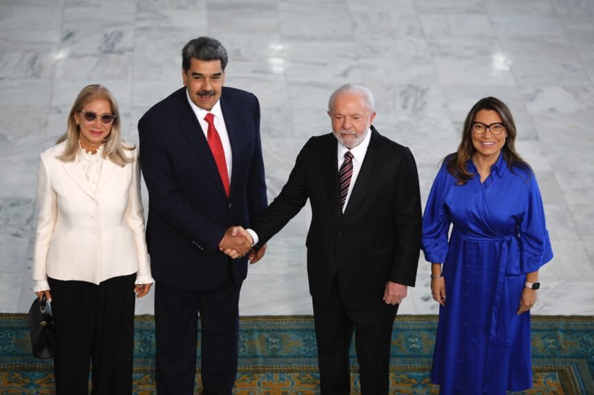 Imagem de uma bandeira do Brasil e da Venezuela se sobrepondo em um fundo de cores neutras.